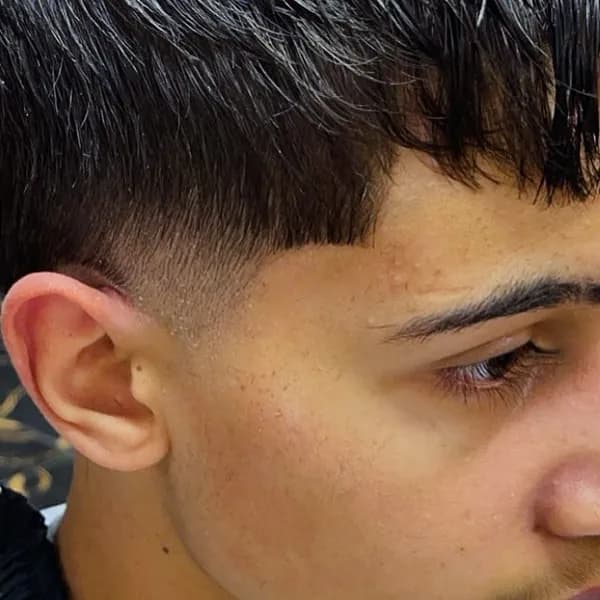 Donker getextureerd haar met fade bij een jonge klant