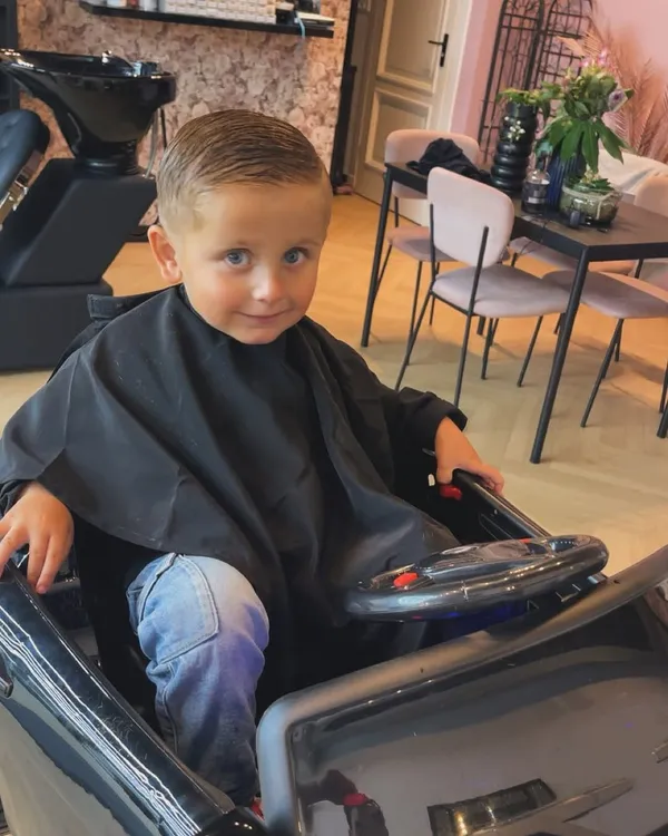 Jong kind in de kapmantel klaar voor het knippen