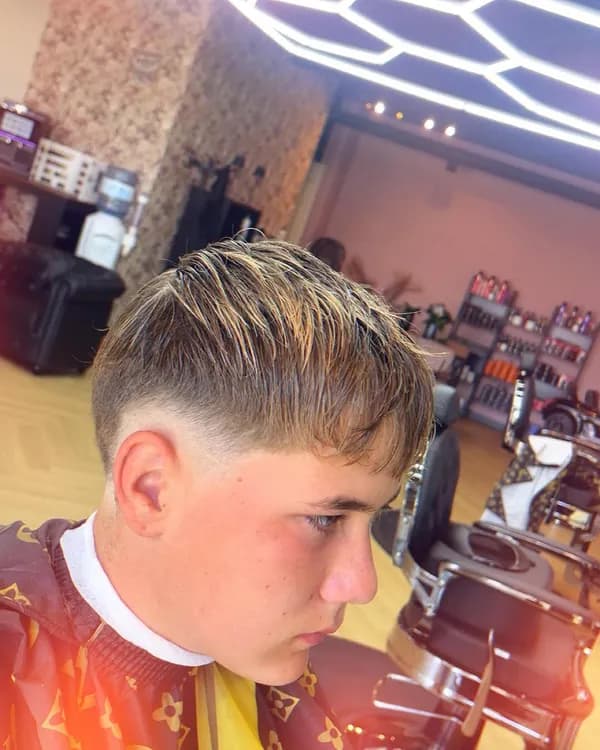 Blond haar met pony en fade bij een jonge klant