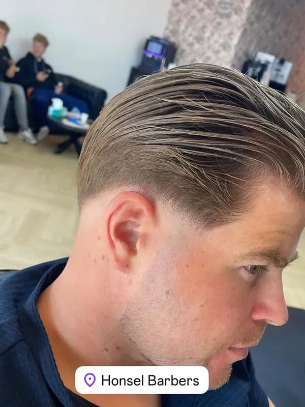 Blond haar naar achteren gekamd met taper aan de zijkant